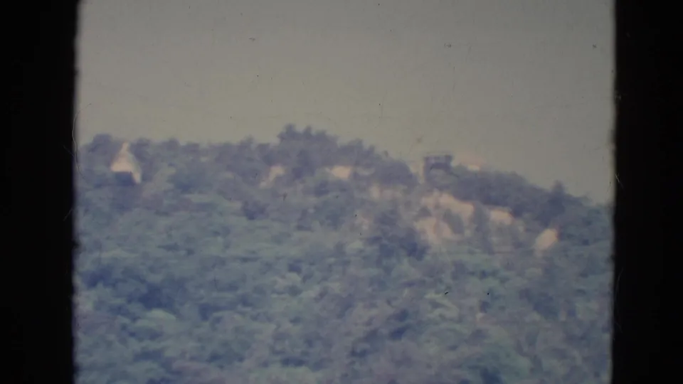 1976 Minnesota 8mm frame showing a soft, distant wooded hillside viewed through a dark window frame.