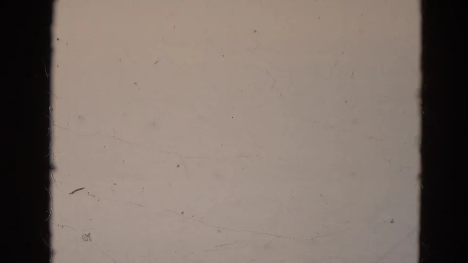 Final 8mm frame appears to show pale blank leader or overexposed film with dark borders and dust marks.