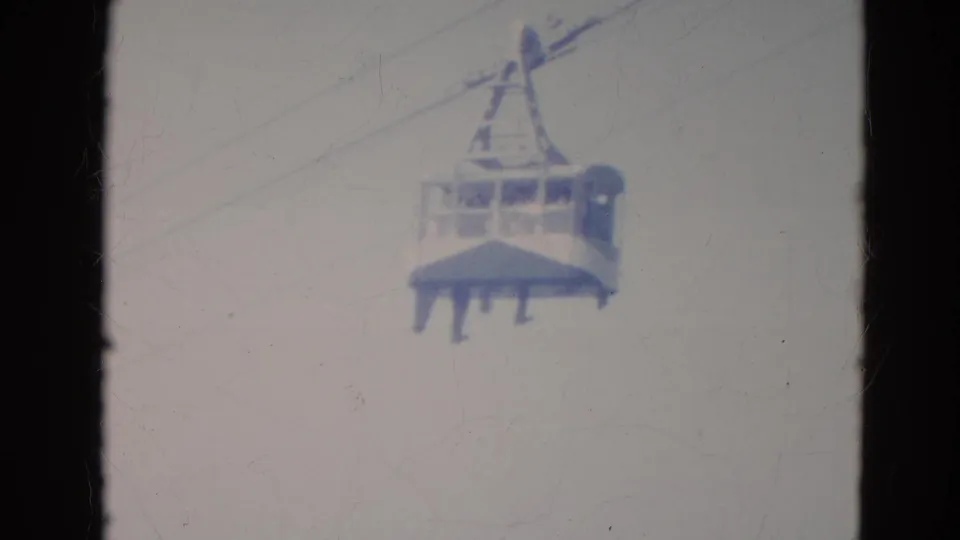 1976 Minnesota 8mm still with a closer gondola cabin, diagonal cables, and passengers barely visible through the windows.
