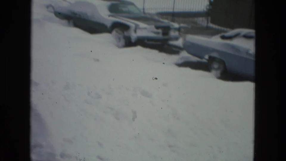 1978 Drexel Hill winter frame showing snow-covered parked cars along a quiet street, with deep drifts filling the foreground.