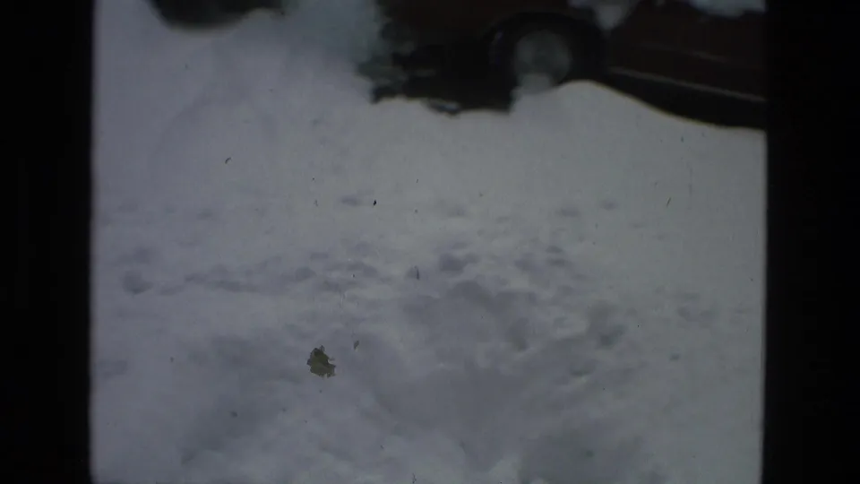 1978 Drexel Hill 8mm frame looking down at a snow-covered residential street with only partial parked cars visible near the upper edge.