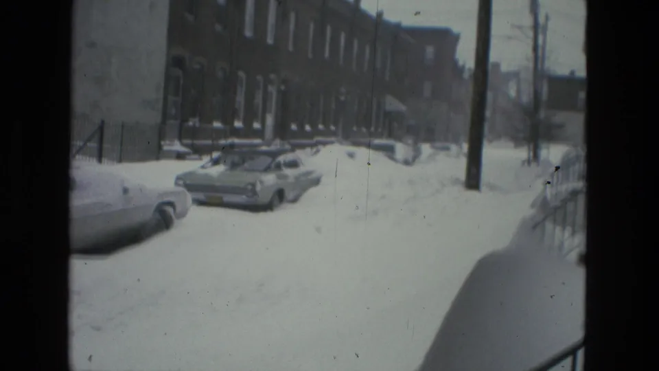 1978 Drexel Hill frame showing row houses, utility poles or trees, parked cars, and a snow-covered residential street viewed from a high front-stoop angle.