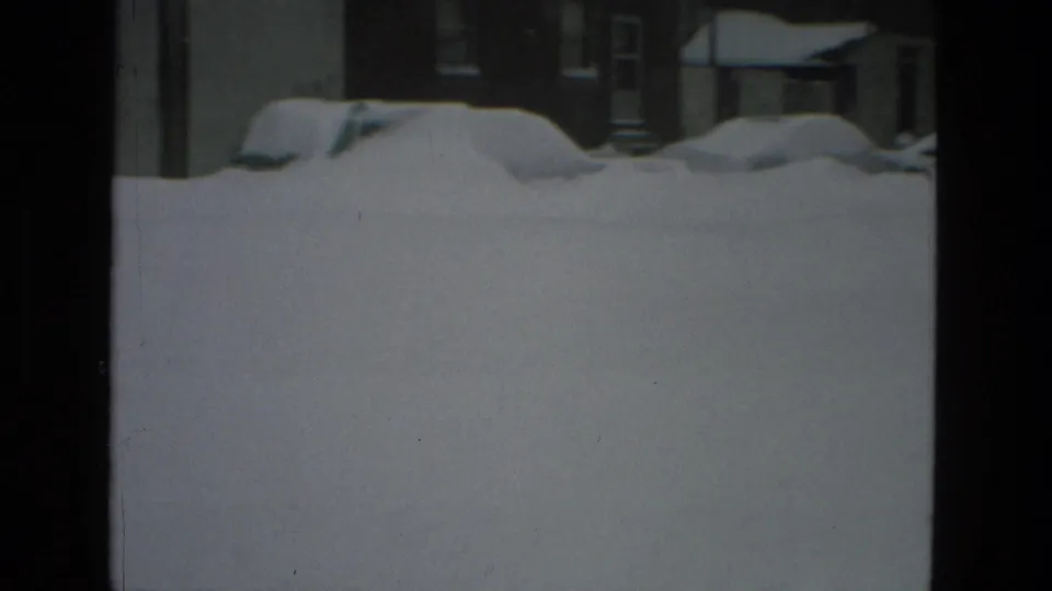 Snow-covered Drexel Hill residential block with buried parked cars and houses mostly obscured by a high snowbank.