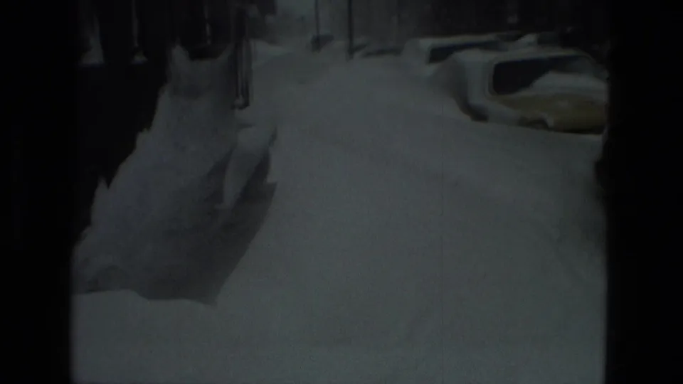 1978 Drexel Hill home-movie frame showing a dim snowy street and parked cars partly covered by deep snow.