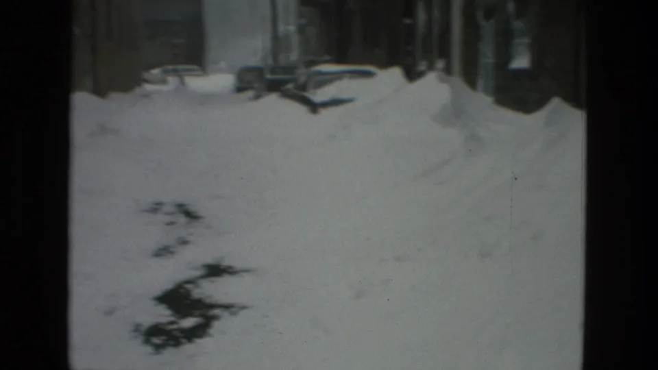 Drexel Hill winter street view with snowbanks, parked cars, and dark foreground shadows in 8mm footage.