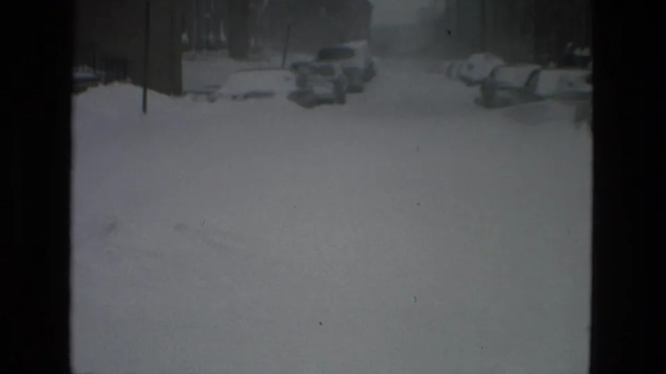 Soft-focus 1978 Drexel Hill street scene showing a snow-covered road and rows of parked cars in the distance.