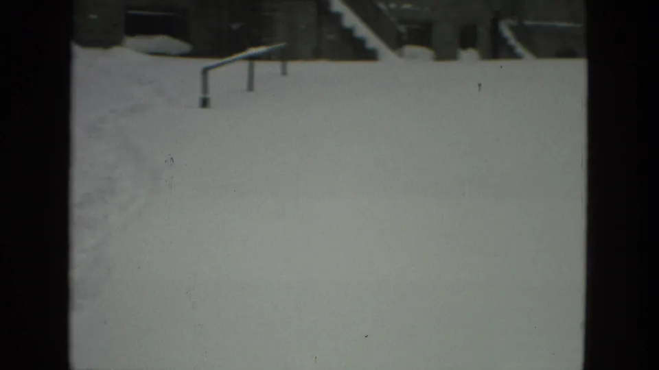 Snow fills the foreground around railings, steps, and residential building fronts in Drexel Hill, Pennsylvania, captured on 8mm film.