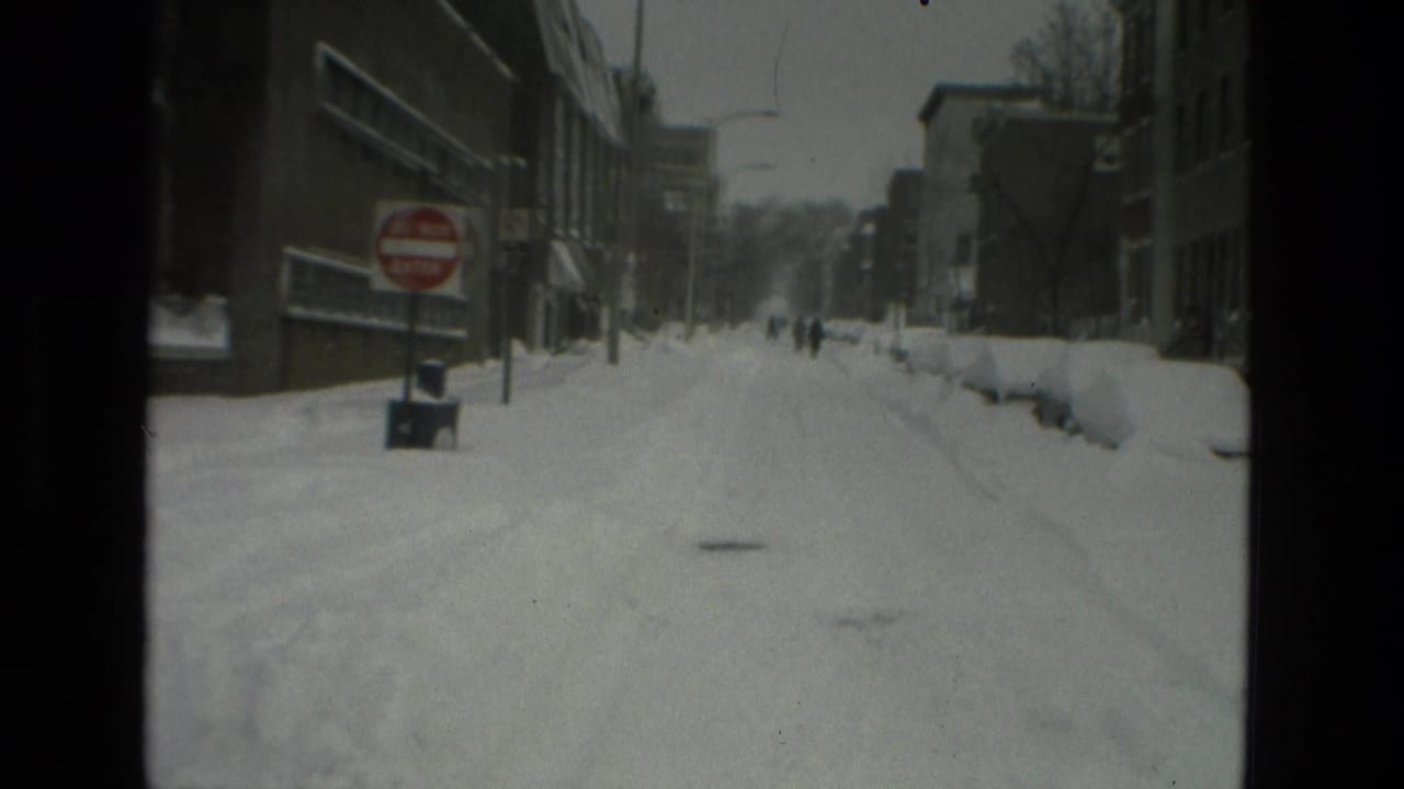 1978 Drexel Hill street scene with deep snow, a red Do Not Enter sign, buildings, and small figures walking in the distance.