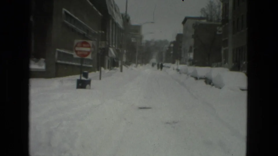 1978 Drexel Hill street scene with deep snow, a red Do Not Enter sign, buildings, and small figures walking in the distance.