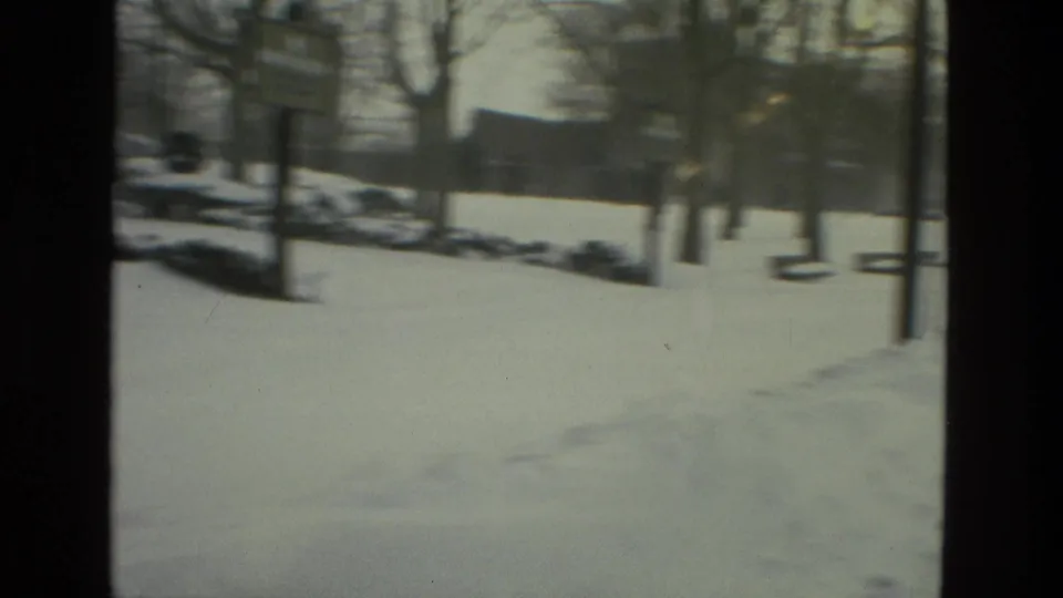 Soft 8mm view of a Drexel Hill snow-covered park with benches, vertical posts, bare trees, and a snowbank along the edge.