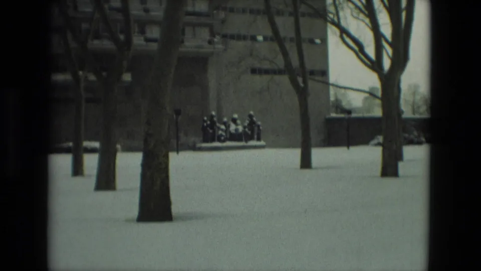 Snow-covered grounds in Drexel Hill, Pennsylvania, with bare trees and the sculpture visible at a distance near a large building.