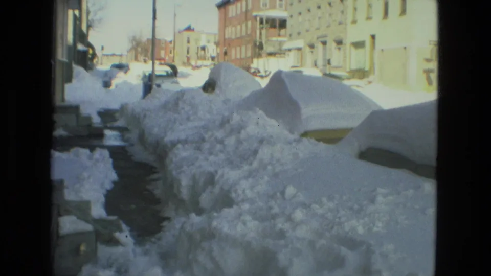 Drexel Hill residential block in 1978 with deep shoveled snowbanks, snow-buried cars, steps, sidewalk, and apartment or row buildings.