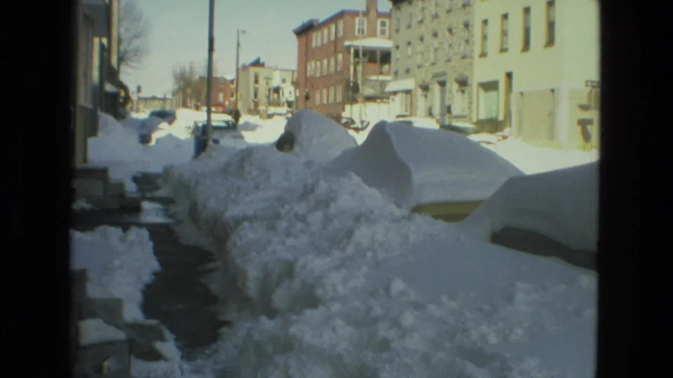 A Drexel Hill residential block appears under heavy 1978 winter snow, with parked cars buried along the curb and brick houses visible in bright daylight.