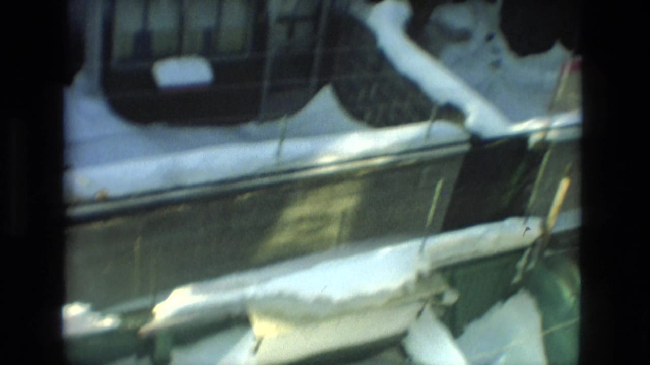 Snow piled along a roof edge and eaves near a windowed house exterior.