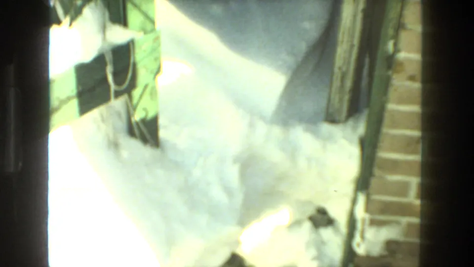 Snow gathers beside a brick wall and wood-trimmed exterior area in Drexel Hill, with a dark object near the snow.