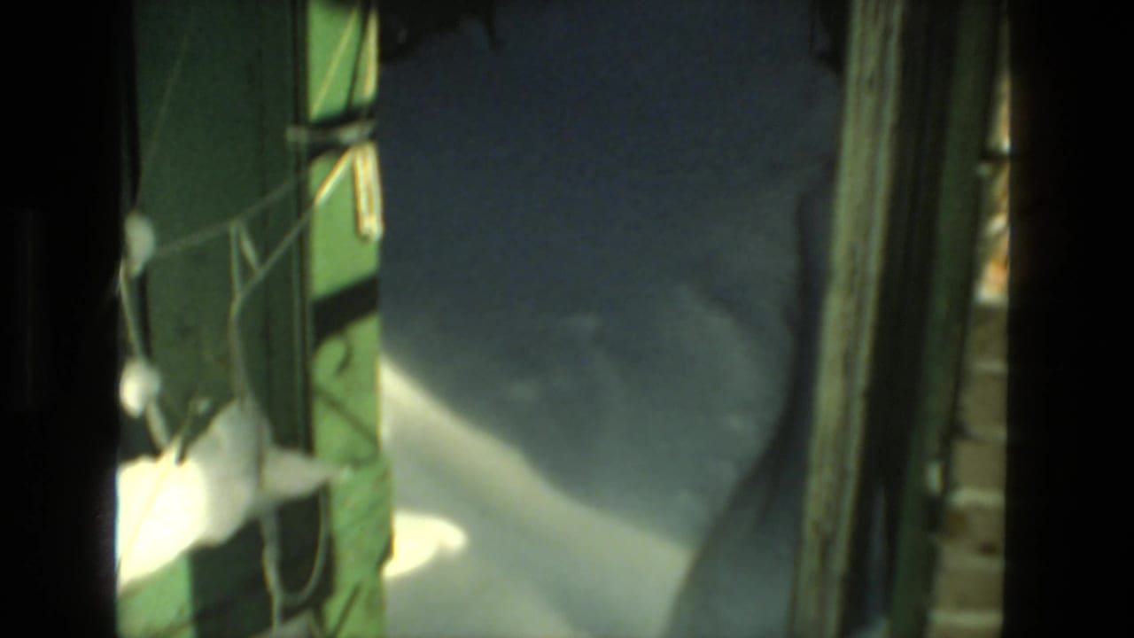 1978 Drexel Hill 8mm frame showing deep snow beside green painted wood and a shadowed residential exterior passage.