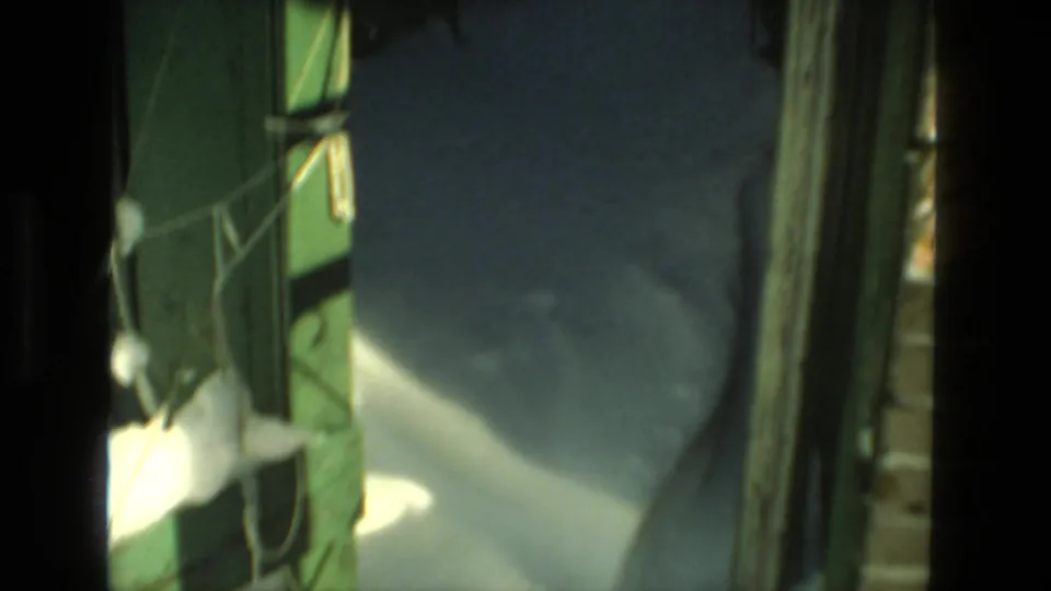 1978 Drexel Hill 8mm frame showing deep snow beside green painted wood and a shadowed residential exterior passage.