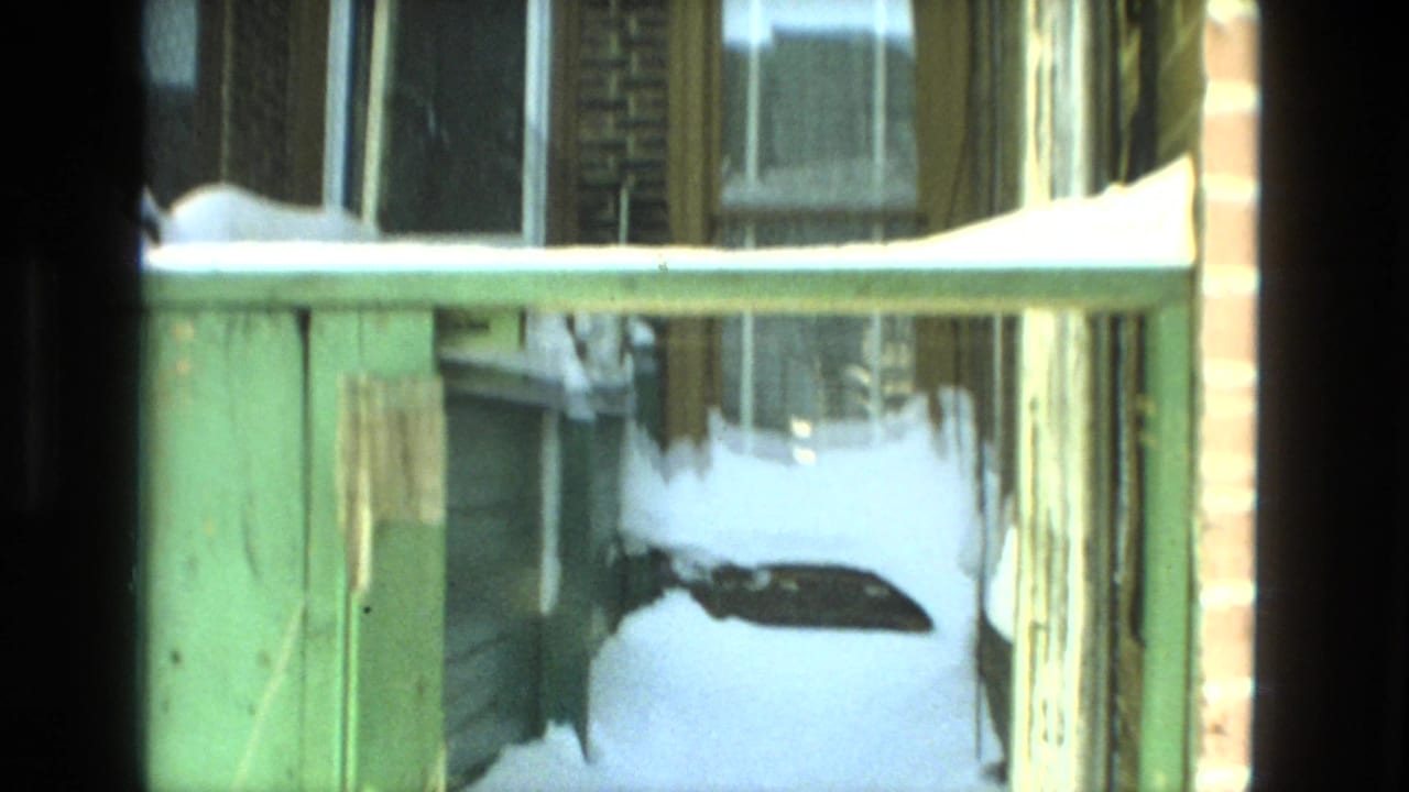 1978 Drexel Hill frame with snow gathered along a green railing, brick walls, and residential windows.