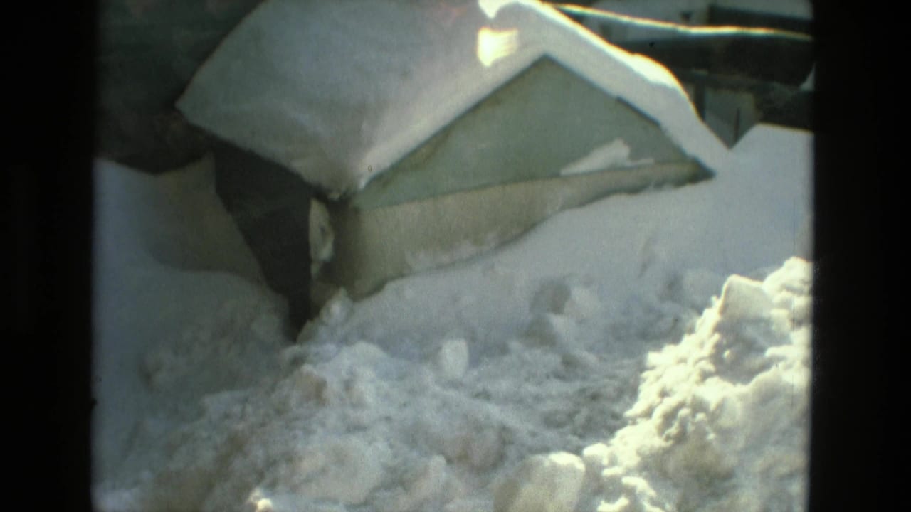 1978 Drexel Hill home-movie frame showing deep snow around a residential roof, yard, and nearby structure.