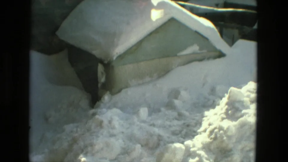 1978 Drexel Hill home-movie frame showing deep snow around a residential roof, yard, and nearby structure.