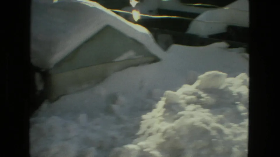 A shaky 8mm view of deep snow against a Drexel Hill residential roof and snowbank in winter light.