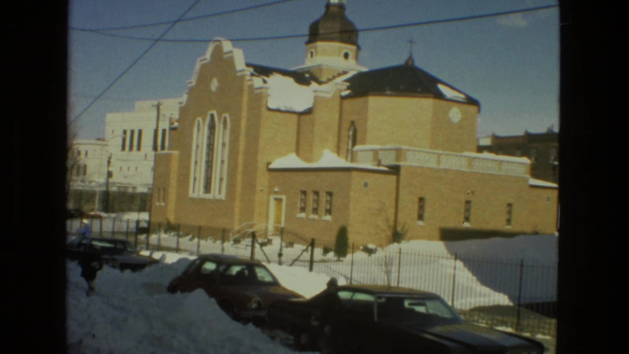 Brick church and parked cars beside deep snowbanks on a winter street.