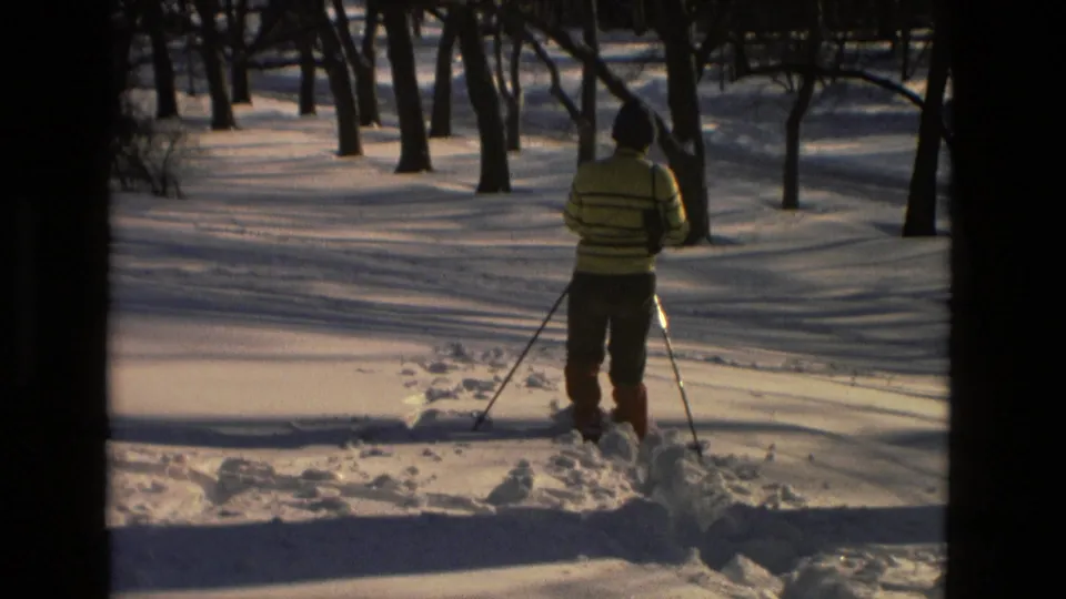 Drexel Hill 1978 frame of a skier in a striped sweater and red leg warmers using poles in snowy woods.