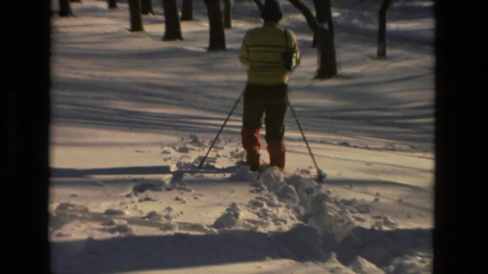 A 1978 home-movie frame shows a skier from behind navigating deep snow in Drexel Hill woods.