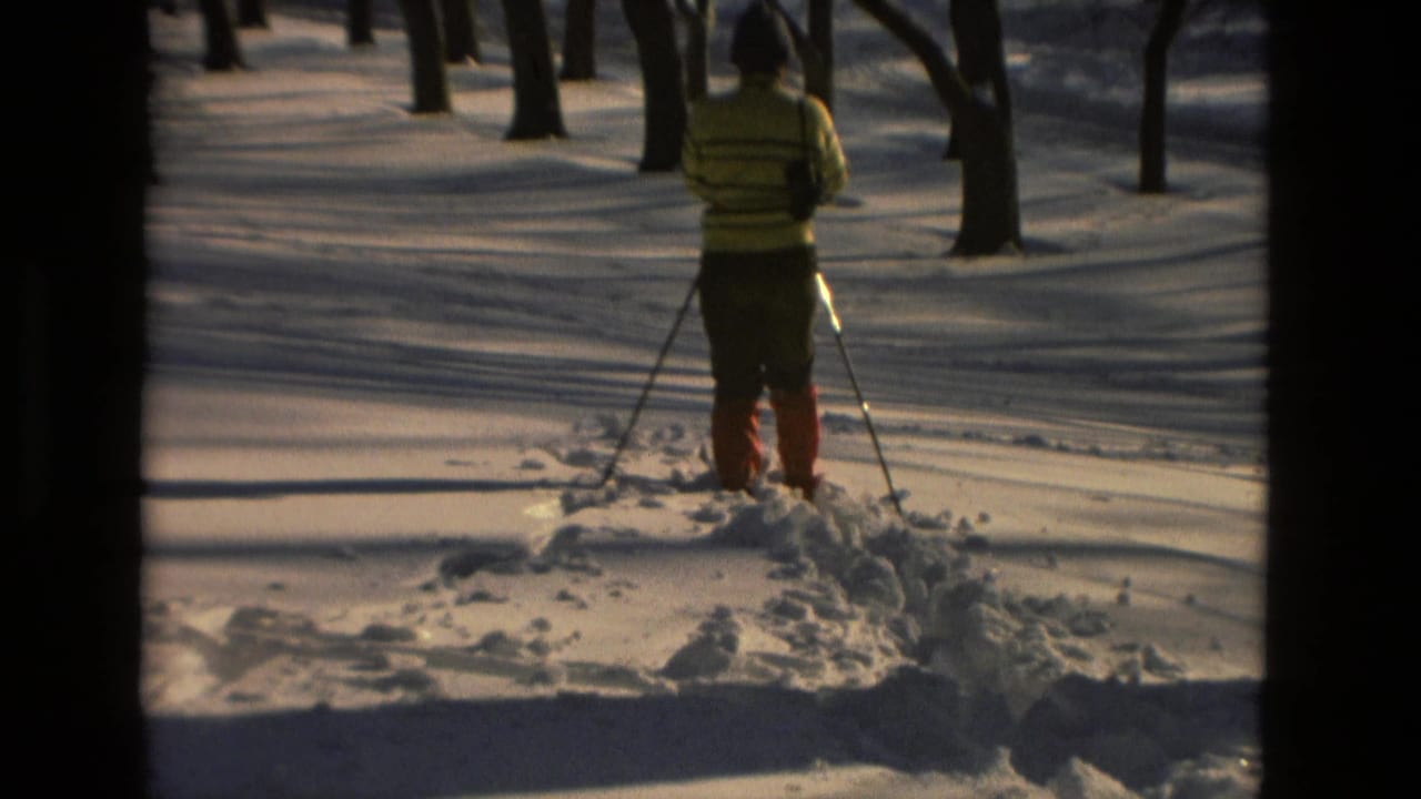 1978 Drexel Hill 8mm frame showing a skier in a yellow striped sweater and red boots facing away in a snowy wooded area.