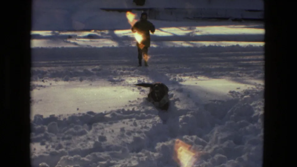 1978 Drexel Hill 8mm frame with a dog crossing deep snow and a bundled adult moving in the background.