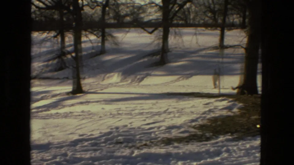 1978 Drexel Hill winter frame showing a quiet snow-covered hillside, bare trees, tracks in the snow, and warm 8mm exposure.