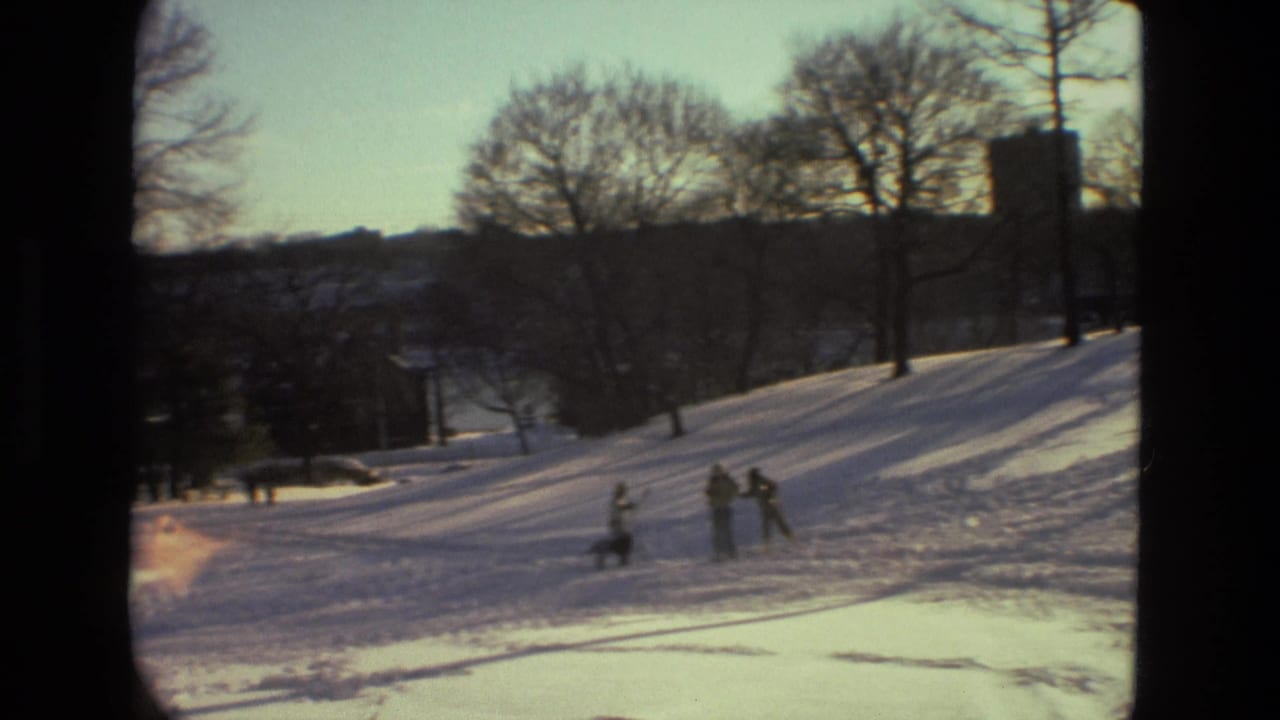 1978 Drexel Hill winter park scene with bundled figures on a snowy slope, bare trees, and a distant building silhouette.