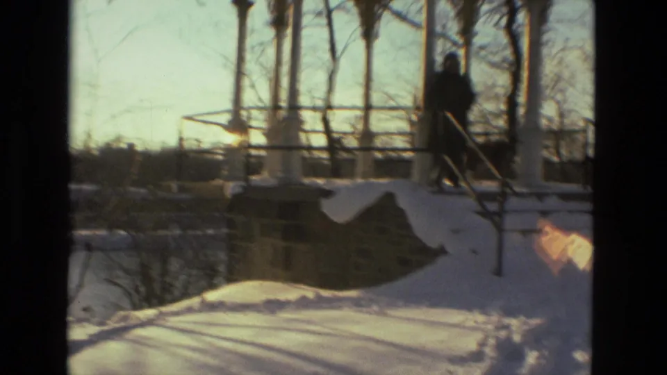 A bundled figure moves along the snowy gazebo steps while a dog stands near the railing in the Drexel Hill winter footage.