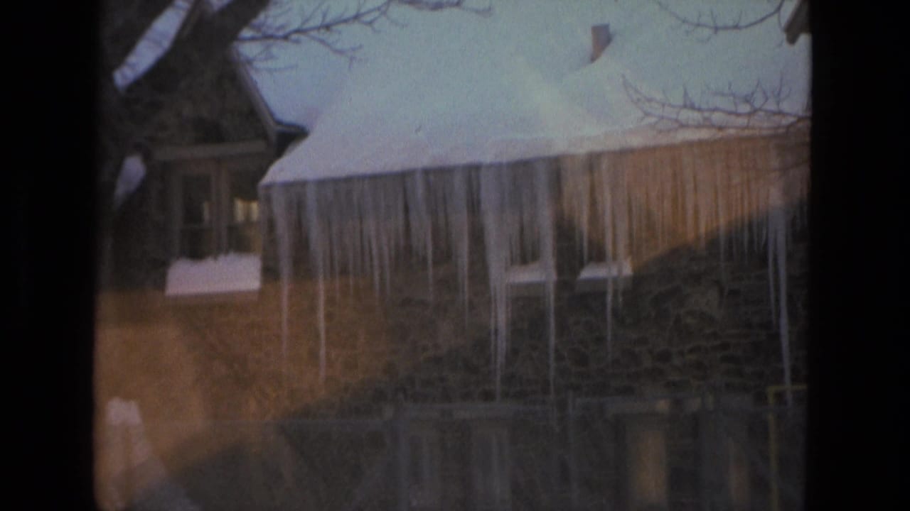 1978 Drexel Hill exterior view of a stone house with snow on the roof and long icicles hanging from the eaves.