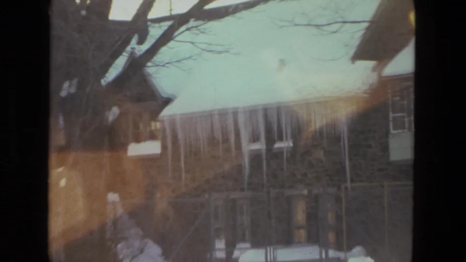Drexel Hill 1978 frame showing a stone residential exterior, bare branches, icicles, and warm flare from winter sun.