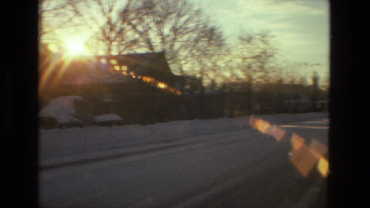 1978 Drexel Hill home-movie view of low sun, bare trees, snowbanks, and parked cars along a residential street.