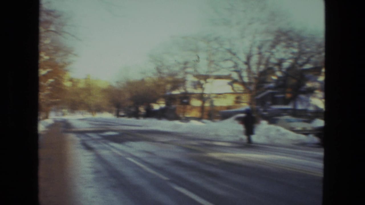 Drexel Hill residential street in 1978 with snow on the road, bare trees, parked cars, and a lone distant pedestrian.