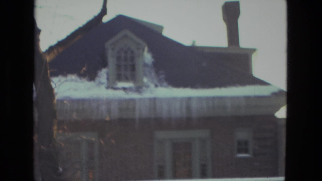 Snow-laden brick residence in Drexel Hill, Pennsylvania, with icicles hanging from the roof edge and a dark upper dormer.