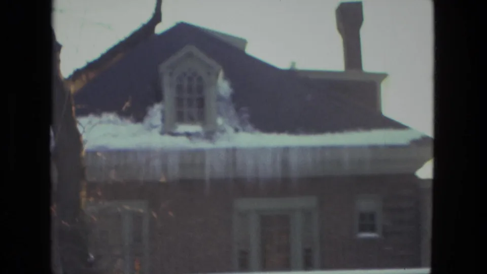 Snow-laden brick residence in Drexel Hill, Pennsylvania, with icicles hanging from the roof edge and a dark upper dormer.