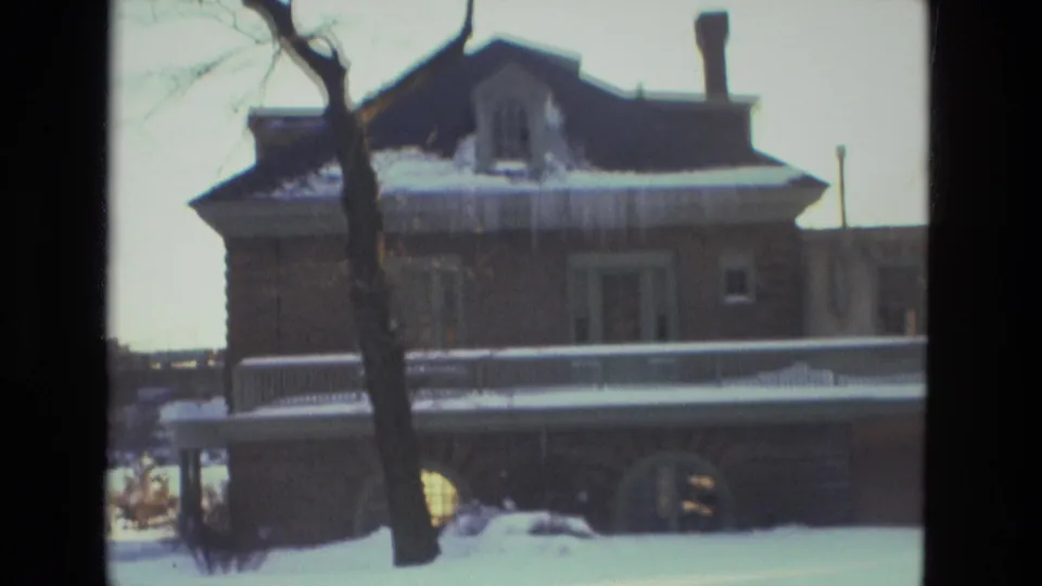 1978 Drexel Hill home exterior with snow on the roof, a bare tree in front, porch railing, and soft 8mm winter exposure.