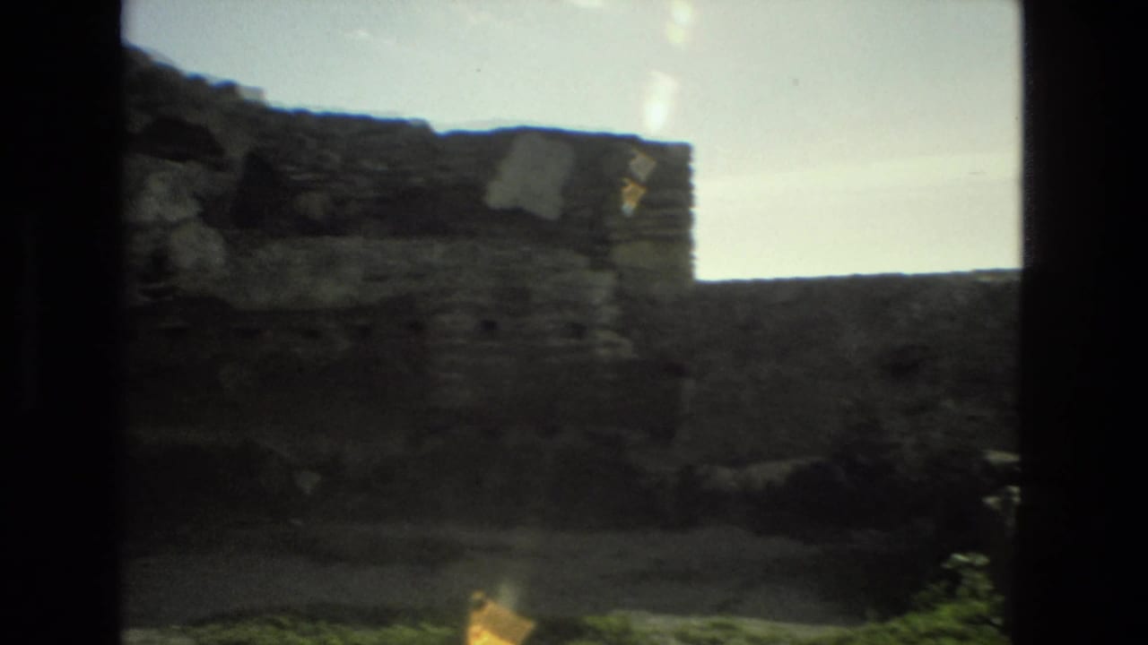 Handheld 8mm view in Granada showing worn stone wall sections, rubble-like masonry, and bright sky.