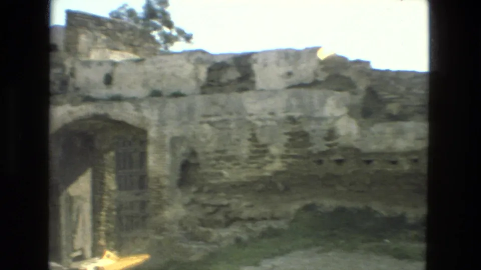 1978 Granada frame of a weathered stone structure with an arched opening, damaged wall top, and uneven ground.