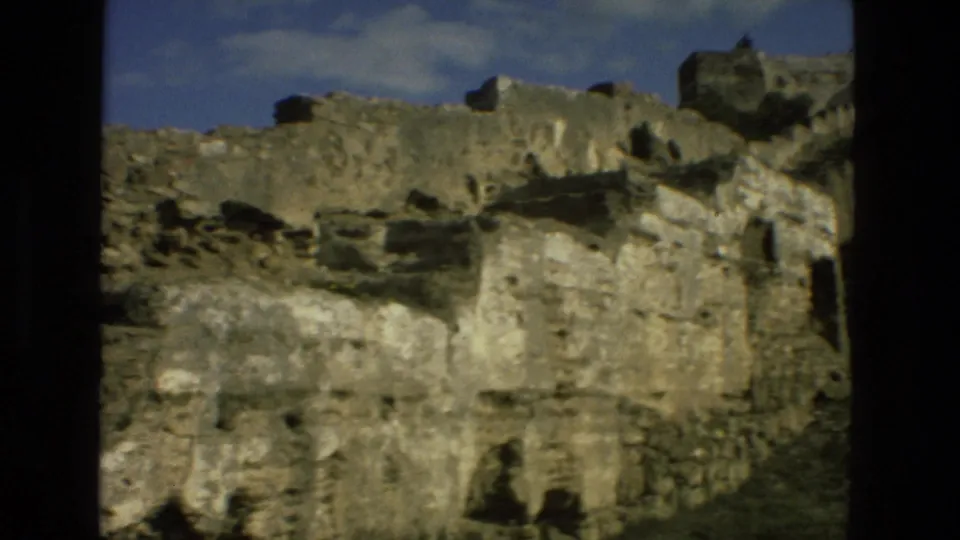1978 8mm close view of Granada stone ruins, showing eroded walls, small openings, and uneven masonry.