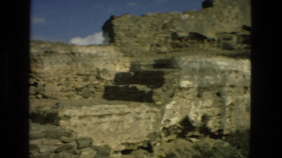 Granada hillside ruins in 1978 8mm footage, with stepped stonework, low walls, rock layers, and a strip of sky.