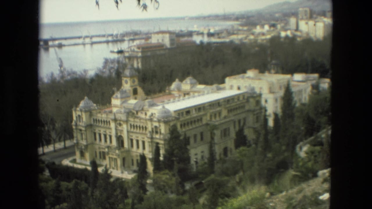 The 1978 Granada home-movie view centers on a large ornate building with domes and a clock tower, set among trees with water and cranes in the background.