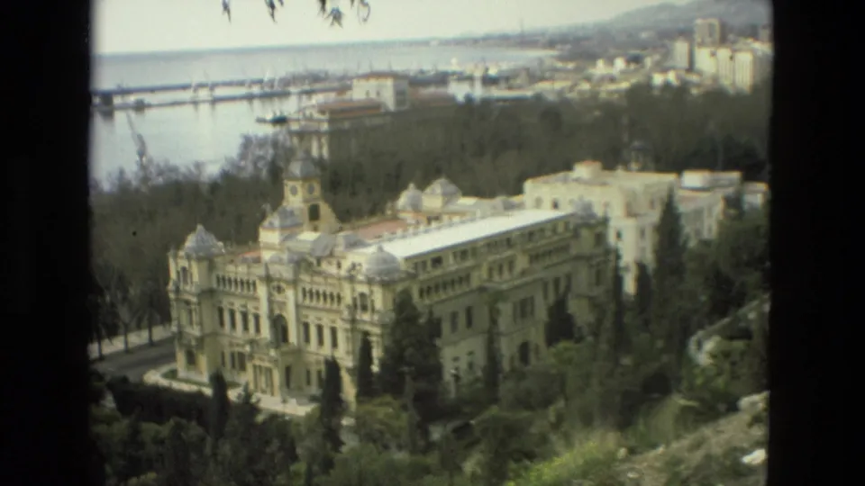 The 1978 Granada home-movie view centers on a large ornate building with domes and a clock tower, set among trees with water and cranes in the background.