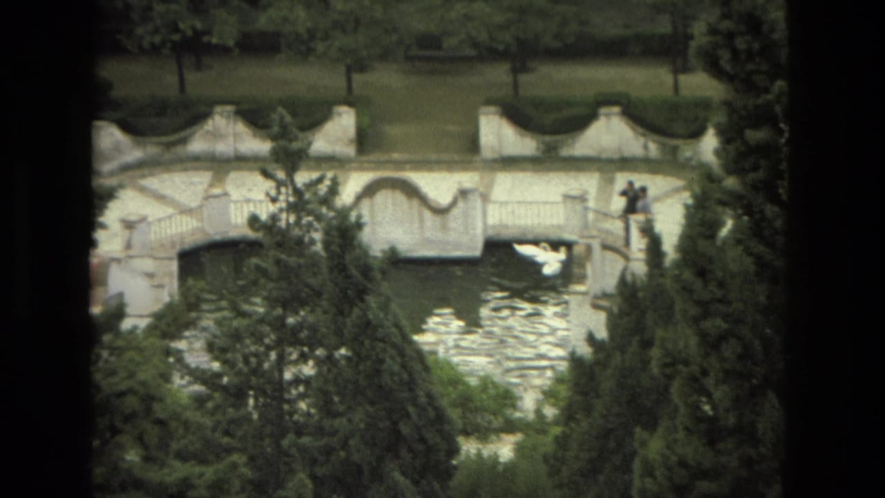 1978 Granada garden footage showing the white ornamental bridge, water below, distant visitors, and a white bird crossing the frame.