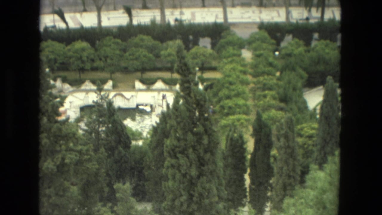 1978 Granada home-movie frame looking over dense trees toward a white ornamental bridge and waterway beyond.