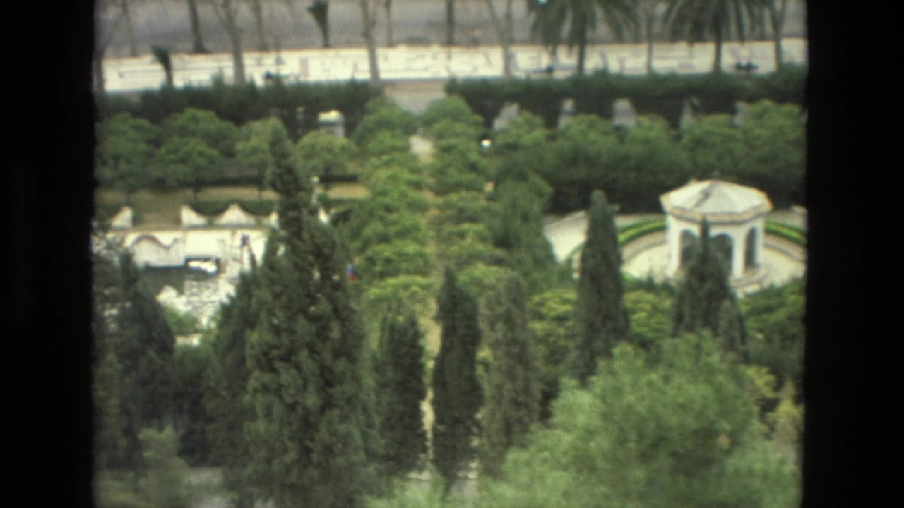 Elevated view of a formal garden with cypress trees, hedges, and a small white pavilion.
