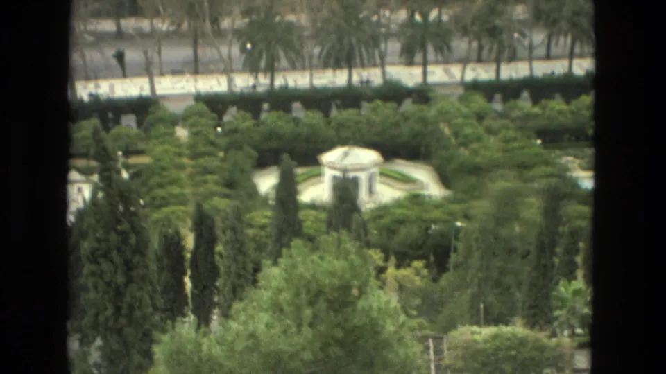 Elevated 1978 Granada view across a green formal garden, with a small white pavilion, tall trees, and a road behind it.